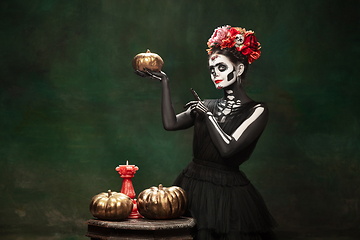 Image showing Young girl in the image of Santa Muerte, Saint death or Sugar skull with bright make-up. Portrait isolated on studio background.