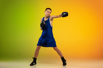 Image showing Teenage boxer against gradient neon studio background in motion of kicking, boxing