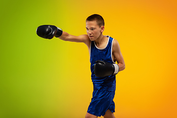 Image showing Teenage boxer against gradient neon studio background in motion of kicking, boxing