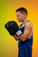 Image showing Teenage boxer against gradient neon studio background in motion of kicking, boxing