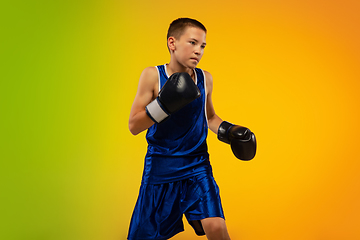 Image showing Teenage boxer against gradient neon studio background in motion of kicking, boxing