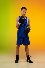 Image showing Teenage boxer against gradient neon studio background in motion of kicking, boxing