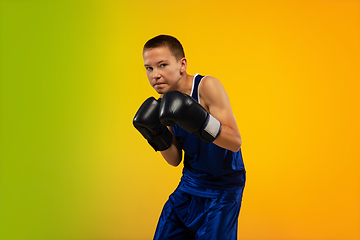 Image showing Teenage boxer against gradient neon studio background in motion of kicking, boxing