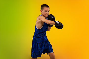 Image showing Teenage boxer against gradient neon studio background in motion of kicking, boxing