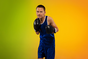 Image showing Teenage boxer against gradient neon studio background in motion of kicking, boxing