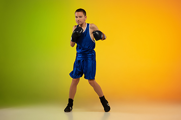 Image showing Teenage boxer against gradient neon studio background in motion of kicking, boxing