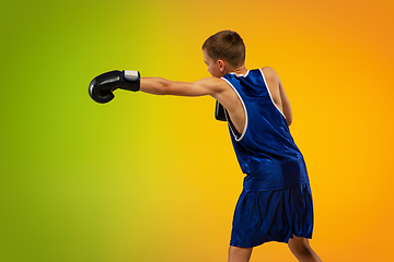 Image showing Teenage boxer against gradient neon studio background in motion of kicking, boxing