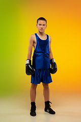 Image showing Teenage boxer against gradient neon studio background in motion of kicking, boxing