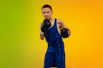 Image showing Teenage boxer against gradient neon studio background in motion of kicking, boxing