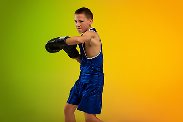 Image showing Teenage boxer against gradient neon studio background in motion of kicking, boxing