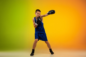 Image showing Teenage boxer against gradient neon studio background in motion of kicking, boxing