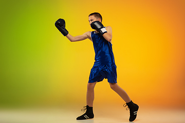 Image showing Teenage boxer against gradient neon studio background in motion of kicking, boxing