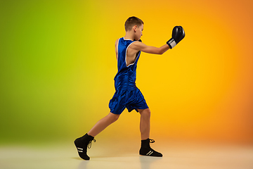 Image showing Teenage boxer against gradient neon studio background in motion of kicking, boxing