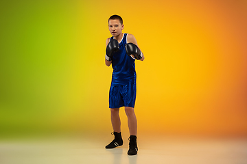 Image showing Teenage boxer against gradient neon studio background in motion of kicking, boxing