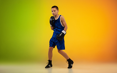 Image showing Teenage boxer against gradient neon studio background in motion of kicking, boxing