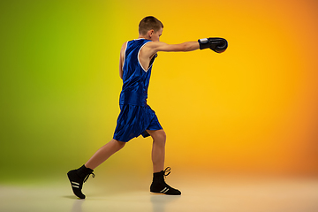 Image showing Teenage boxer against gradient neon studio background in motion of kicking, boxing