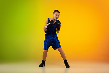 Image showing Teenage boxer against gradient neon studio background in motion of kicking, boxing