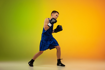 Image showing Teenage boxer against gradient neon studio background in motion of kicking, boxing