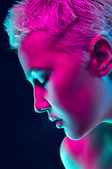 Image showing Portrait of female fashion model in neon light on dark studio background.