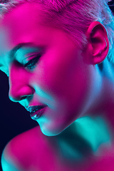 Image showing Portrait of female fashion model in neon light on dark studio background.