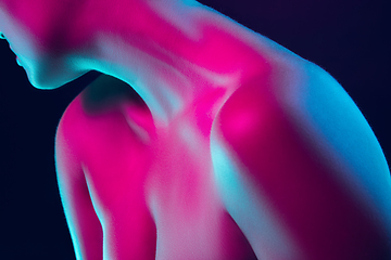 Image showing Portrait of female fashion model in neon light on dark studio background.