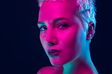 Image showing Portrait of female fashion model in neon light on dark studio background.