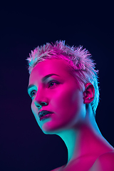 Image showing Portrait of female fashion model in neon light on dark studio background.