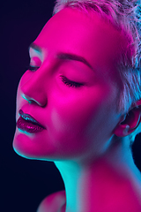 Image showing Portrait of female fashion model in neon light on dark studio background.