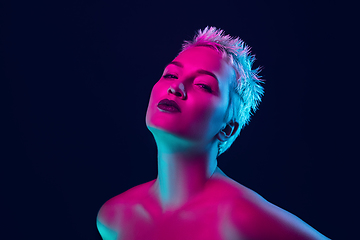 Image showing Portrait of female fashion model in neon light on dark studio background.