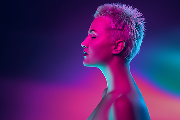 Image showing Portrait of female fashion model in neon light on dark studio background.