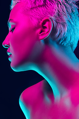 Image showing Portrait of female fashion model in neon light on dark studio background.