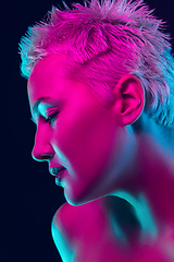 Image showing Portrait of female fashion model in neon light on dark studio background.