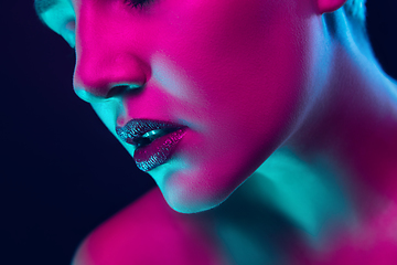 Image showing Portrait of female fashion model in neon light on dark studio background.