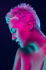 Image showing Portrait of female fashion model in neon light on dark studio background.