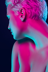 Image showing Portrait of female fashion model in neon light on dark studio background.