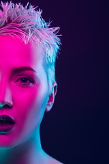 Image showing Portrait of female fashion model in neon light on dark studio background.