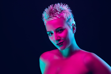 Image showing Portrait of female fashion model in neon light on dark studio background.