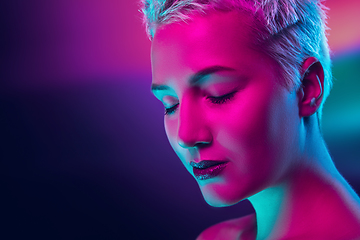 Image showing Portrait of female fashion model in neon light on dark studio background.