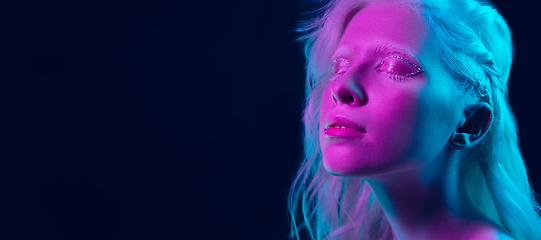 Image showing Portrait of beautiful albino girl isolated on dark studio background in neon light