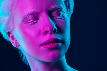 Image showing Portrait of beautiful albino girl isolated on dark studio background in neon light