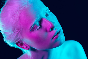 Image showing Portrait of beautiful albino girl isolated on dark studio background in neon light