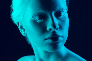 Image showing Portrait of beautiful albino girl isolated on dark studio background in neon light