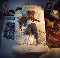 Image showing Portrait of a woman, female breeder sleeping in the bed with her dog at home