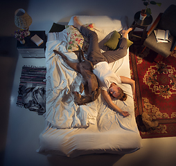 Image showing Portrait of a woman, female breeder sleeping in the bed with her dog at home