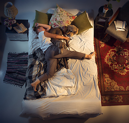 Image showing Portrait of a woman, female breeder sleeping in the bed with her dog at home