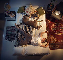 Image showing Portrait of a woman, female breeder sleeping in the bed with her dog at home