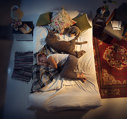 Image showing Portrait of a woman, female breeder sleeping in the bed with her dog at home