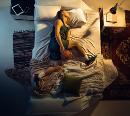 Image showing Top view of young professional basketball player sleeping at his bedroom in sportwear with ball