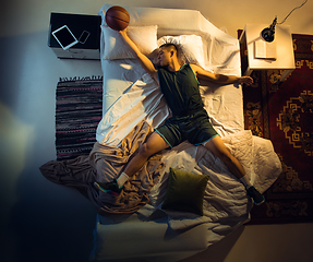 Image showing Top view of young professional basketball player sleeping at his bedroom in sportwear with ball