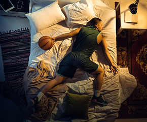 Image showing Top view of young professional basketball player sleeping at his bedroom in sportwear with ball